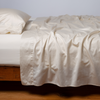 Bria Twin Flat Sheet | Bria flat sheet in parchment, shown with matching fitted sheet and sleeping pillow - side view.
