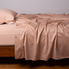 Bria Twin Flat Sheet | Rouge | Cotton sateen flat sheet, shown with matching fitted sheet and sleeping pillow - side view.