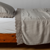 Madera Luxe Pillowcase (Single) | Fog | matching tencel pillowcase and flat sheet trimmed with cotton lace on a bed shown from the side view.