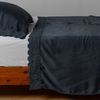 Madera Luxe Pillowcase (Single) | Midnight | matching tencel pillowcase and flat sheet trimmed with cotton lace on a bed shown from the side view.