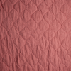 Austin Coverlet | Poppy | A close up of quilted midweight linen fabric in poppy, a warm coral pink.