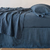 Austin bed skirt in midnight shown from the side on a bed with monochromatic sheeting, highlighting its tailored, ungathered style.