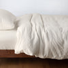 Austin Duvet Cover | Parchment | Midweight linen duvet cover in parchment on a bed, side view.