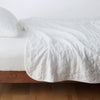 Austin Coverlet | Winter White | Quilted midweight linen coverlet in winter white on a bed - side view.