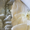 Close-up of Linen whisper duvet cover in mineral, layered over winter white linen sheets, showcasing ruffle trim detail.