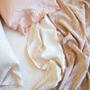 Close-up of rumpled Vienna coverlet with linen sheets and sleeping pillows - in pink and cream tones - overhead view.