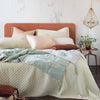 Taline Throw Pillow | Taline silk charmeuse pairs beautifully with silk velvet and quilted silk velvet in pale cream, pink, and blue tones with mahogany accents - end of bed view.