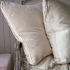 Harlow Throw Pillow | Close up of Harlow 24 by 24 pillow, arranged on an antique sofa with complementary textures of linen and charmeuse, all in parchment.