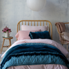 Bria Twin Duvet Cover | Foot of bed view of the soft pink cotton sateen duvet cover layered with quilted charmeuse, silk velvet, and linen in pink and rich blue green tones.
