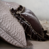 Cirillo Sham | close up of the side view of a quilted cotton sateen sham with silk velvet throw pillow with raw edges propped up against the pillow sham - both in grey tones.