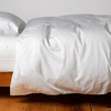 Bria Duvet Cover | Winter White | duvet cover and matching sleeping pillow on white sheeting - side view.