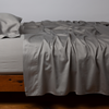 Bria Flat Sheet | Moonlight | Cotton sateen flat sheet, shown with matching fitted sheet and sleeping pillow - side view.