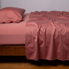 Bria Flat Sheet | Poppy | Cotton sateen flat sheet, shown with matching fitted sheet and sleeping pillow - side view.