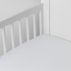 Bria Crib Sheet | White | Cotton sateen crib sheet shown from a slight overhead angle into  an inside corner of a crib.