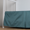 Bria Crib Skirt | Cenote | cotton sateen cribi skirt with a center pleat shown straight on from a slight angle in a crib without a crib mattress.