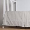 Bria Crib Skirt | Cloud | cotton sateen cribi skirt with a center pleat shown straight on from a slight angle in a crib without a crib mattress.