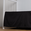 Bria Crib Skirt | Corvino | cotton sateen cribi skirt with a center pleat shown straight on from a slight angle in a crib without a crib mattress.