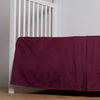 Bria Crib Skirt | Fig | cotton sateen cribi skirt with a center pleat shown straight on from a slight angle in a crib without a crib mattress.