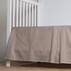 Bria Crib Skirt | Fog | cotton sateen cribi skirt with a center pleat shown straight on from a slight angle in a crib without a crib mattress.