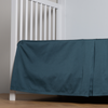 Bria Crib Skirt | Midnight | cotton sateen cribi skirt with a center pleat shown straight on from a slight angle in a crib without a crib mattress.