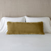 Carmen Throw Pillow | Honeycomb | Silk velvet lumbar pillow with petite ruffle, leaning upright against neutral bedding and headboard.