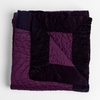 Cirillo Blanket | Fig | a folded quilted cotton sateen throw blanket with its corner folded down to show the trim contrast - shot against a white background.