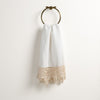 Frida Guest Towel | Winter White | Lace trimmed linen guest towel  draped through a decorative towel ring against a plain white background.