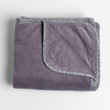 Harlow Blanket | French Lavender | cotton velvet blanket trimmed with charmeuse, folded with a corner folded back to show trim contrast; shot overhead at a slight angle against a white background.