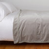 Harlow Blanket | Fog | Cotton velvet blanket, draped on a white bed with corner folded back - side view.
