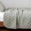 Harlow Coverlet | Eucalyptus | Quilted cotton velvet coverlet draped over a white fitted sheet - side view.