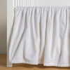 Harlow Crib Skirt | White | cotton velvet crib skirt shown on a white crib .