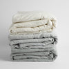 Ines Baby Blanket | a stack of three embroidered linen baby blankets in cool tones | winter white, cloud and eucalyptus