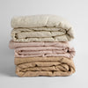Ines Baby Blanket | A stack of three embroidered linen baby blankets in neutral tones | parchment, pearl and honeycomb