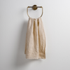 Ines Guest Towel | Parchment | guest towel draped through a decorative brass towel ring against a white background.
