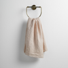 Ines Guest Towel | Pearl | guest towel draped through a decorative brass towel ring against a white background.
