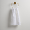 Ines Guest Towel | White | guest towel draped through a decorative brass towel ring against a white background.