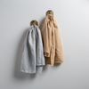 Two Ines guest towels, draped over decorative hooks against a white wall - cloud and honeycomb.