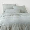 Ines Duvet Cover | Eucalyptus | duvet cover and matching shams against a white wall - end of bed view.