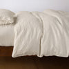 Ines Duvet Cover | Parchment | lightly rumpled duvet cover on a monochromatic bed against a white background - side view.