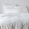 Ines Duvet Cover | Winter White | duvet cover and matching shams against a white wall - end of bed view.