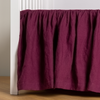 Linen Crib Skirt | Fig | crib skirt shown on a white crib with no mattress against a white wall and medium wood flooring.