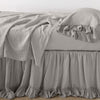 Linen Whisper Bed Skirt | Fog | bed skirt layered with monochromatic linen sheeting - side view.