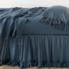 Linen Whisper Bed Skirt | Midnight | bed skirt layered with monochromatic linen sheeting - side view.