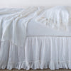 Linen Whisper Bed Skirt | White | bed skirt layered with monochromatic linen sheeting - side view.