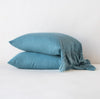 Linen Whisper Pillowcase (Single) | Cenote | Two sleeping pillows stacked at a slight angle against a plain background, showcasing ruffle trim detail - side view.