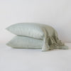 Linen Whisper Pillowcase (Single) | Eucalyptus | Two sleeping pillows stacked at a slight angle against a plain background, showcasing ruffle trim detail - side view.