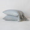 Linen Whisper Pillowcase (Single) | Mineral | Two sleeping pillows stacked at a slight angle against a plain background, showcasing ruffle trim detail - side view.
