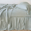 Linen Bed Skirt | Eucalyptus | bed skirt with matching rumpled sheets and sleeping pillows - side view.