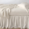 Linen Twin Bed Skirt | Parchment | bed skirt with matching rumpled sheets and sleeping pillows - side view.