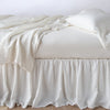 Linen Bed Skirt | Winter White | bed skirt with matching rumpled sheets and sleeping pillows - side view.